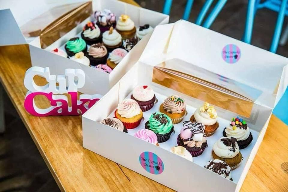 Two open boxes of assorted The Cupcake Desire cupcakes